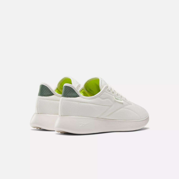 A pair of Reebok Active Lite Shoes in white, featuring light green interiors and dark green textured detailing on the heel, displayed from an angled rear view against a plain white background.