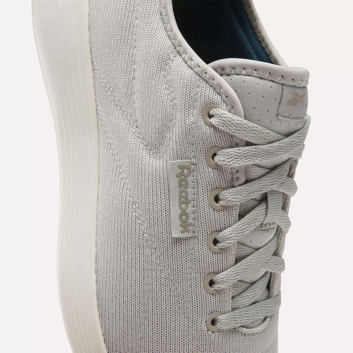 Close-up of light gray Reebok Active Lite Shoes, featuring a minimalist lace-up design, textured fabric, stitched details, and a Reebok tag. The white sole adds to the clean look and lightweight feel of these sneakers.