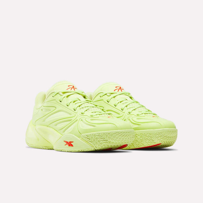 Two light green Angel Reese 1 Shoes for big kids by Reebok, with textured soles and orange logos, are placed side by side. Their modern, sculpted basketball style pops against a plain white background.