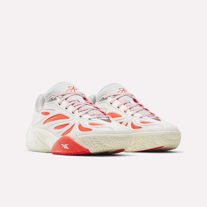 The Reebok Angel Reese 1 Shoes for big kids feature a white base, red and orange accents, mesh details, and textured cream soles, shown side by side against a plain light background.