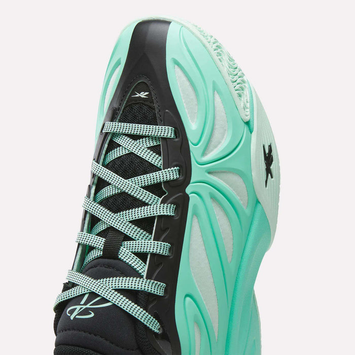 A close-up of the Reebok Angel Reese 1 Basketball Shoes for big kids in black and mint green, showcasing light green laces and the Reebok logo on the tongue, side, and toe. The shoe’s futuristic wavy upper design makes it a standout choice for kids’ basketball footwear.