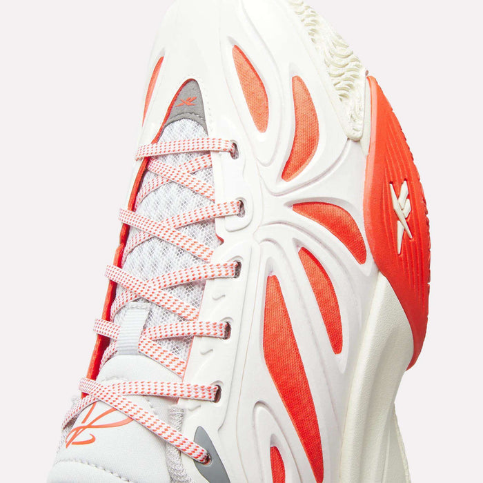 Close-up of the Reebok Angel Reese 1 Shoes for Big Kids—a white athletic sneaker with red-orange accents, textured sole, and patterned laces. The modern mesh and synthetic design makes it ideal for kids' basketball.