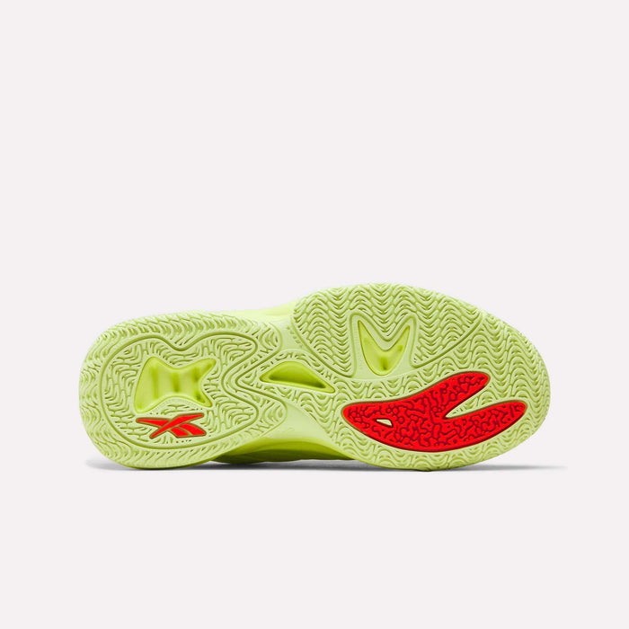 The image features the bright yellow-green sole of the Reebok Angel Reese 1 Shoes for Big Kids, displaying intricate wavy and circular tread patterns with small red accents near the toe area.