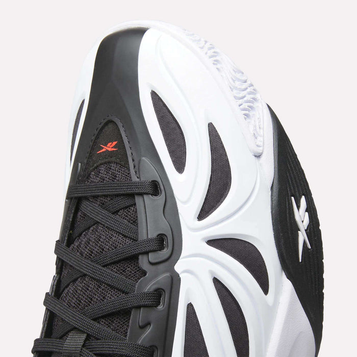 Close-up of the Reebok Angel Reese 1 Basketball Shoes—black and white design with black laces, white outsole, red logo near the toe, wavy patterns, and Energy Return System for peak basketball performance.