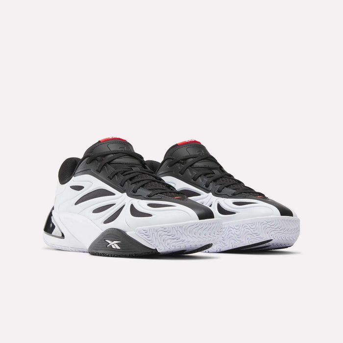 The Reebok Angel Reese 1 Basketball Shoes feature a wavy, futuristic black and white design with a chunky sole, red tongue accents, and Energy Return System for high performance. Shown on a white background.