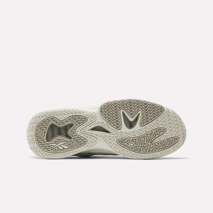 The image displays the outsole of the Reebok Angel Reese 1 Basketball Shoes, with a textured beige and grey tread pattern. Inspired by performance basketball, its wavy lines and grooves provide superior traction for quick court movements.