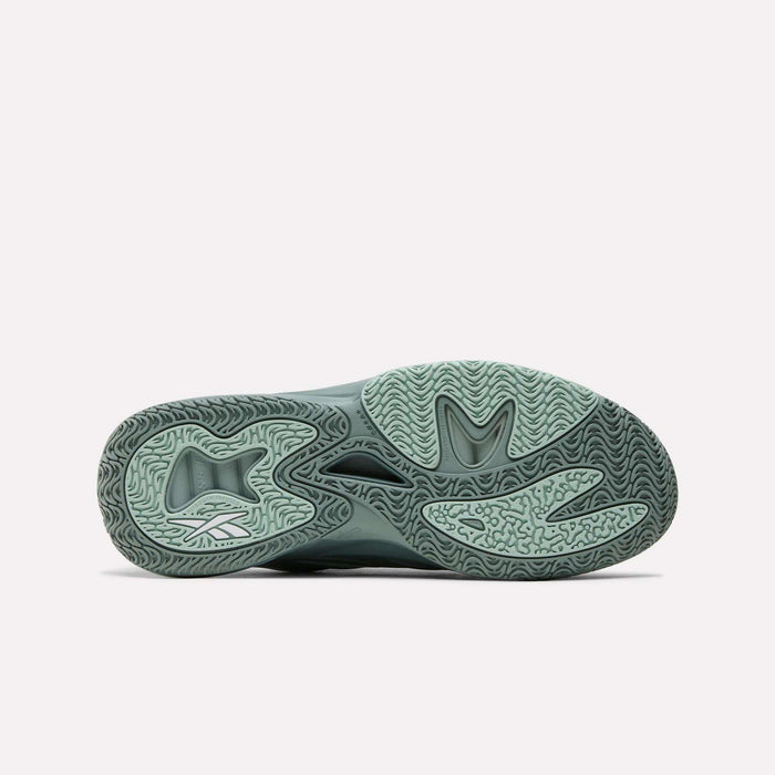 The image shows the light green, textured sole of the Reebok Angel Reese 1 Basketball Shoe, featuring curved patterns, a stylized heel logo, and the Energy Return System, displayed on a plain white background.