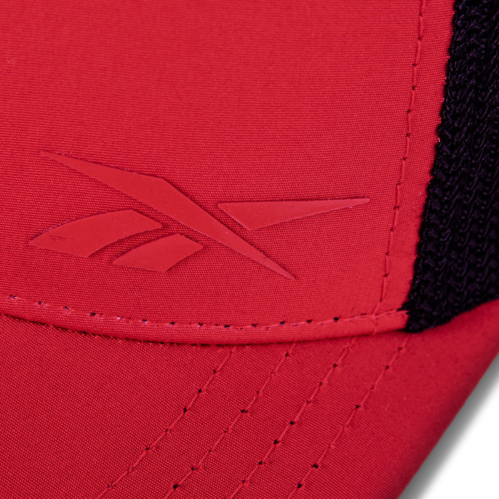 Close-up of the red Reebok Athlete Cap featuring an embossed Reebok logo on the front, black mesh fabric on the side, and detailed stitching along the seam.