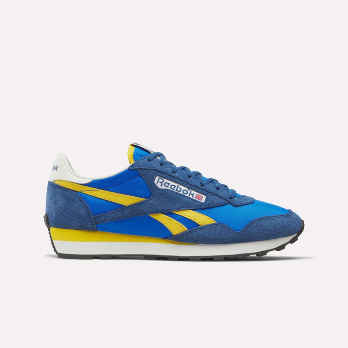 The Reebok Aztec II Shoes feature blue and yellow suede and mesh panels, vintage running shoe style, the Reebok logo with Union Jack on the side, a white heel tab, and a black rubber sole.