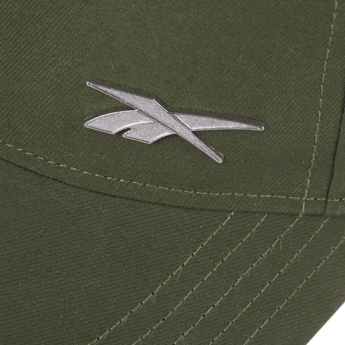 Close-up of the silver Reebok logo on olive green fabric of the Reebok Badge Cap, featuring visible stitching and intersecting seams.