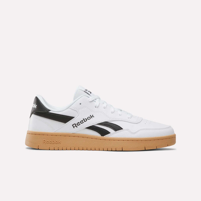 The Reebok BB 1000 Shoes in White/Black/Gum feature a classic leather upper, black Reebok logo accents, and a tan gum sole. Displayed in side profile against a plain white background, these iconic sneakers draw inspiration from classic ’80s heritage style.