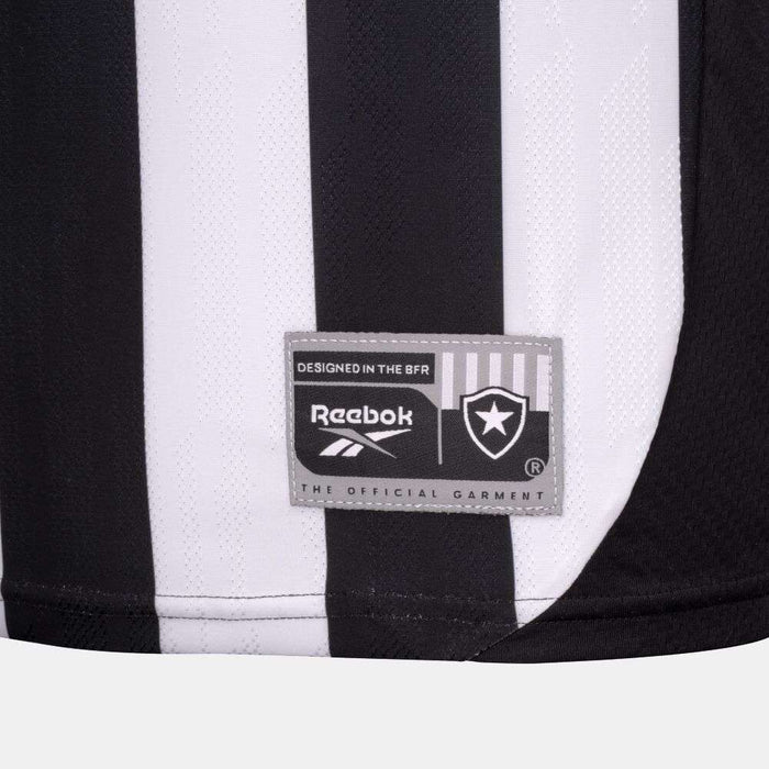Close-up of the Botafogo Men's Home Jersey by Reebok: black and white stripes, gray patch with Reebok logo, shield emblem, and text reading "The Official Garment" and "Designed in the BFR.