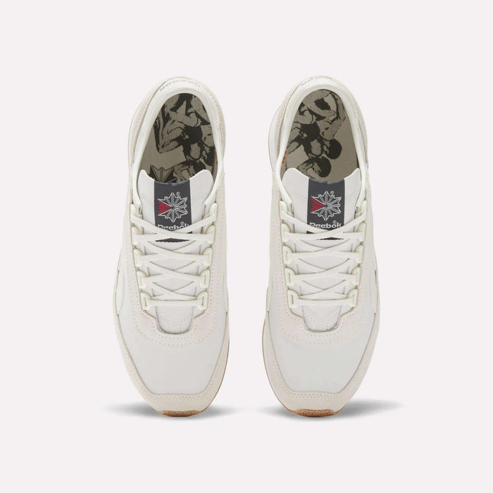 A pair of white Reebok Camargue Shoes viewed from above, with graphic black and white patterned insoles, white laces, and a gray tongue patch featuring the red-and-white Reebok logo for an archive trainer style.