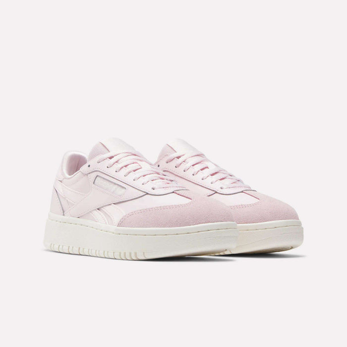 The Reebok Campio XT Double Shoes for Big Kids feature a light pink design with white soles, side stripes, and laces, shown against a plain white background.