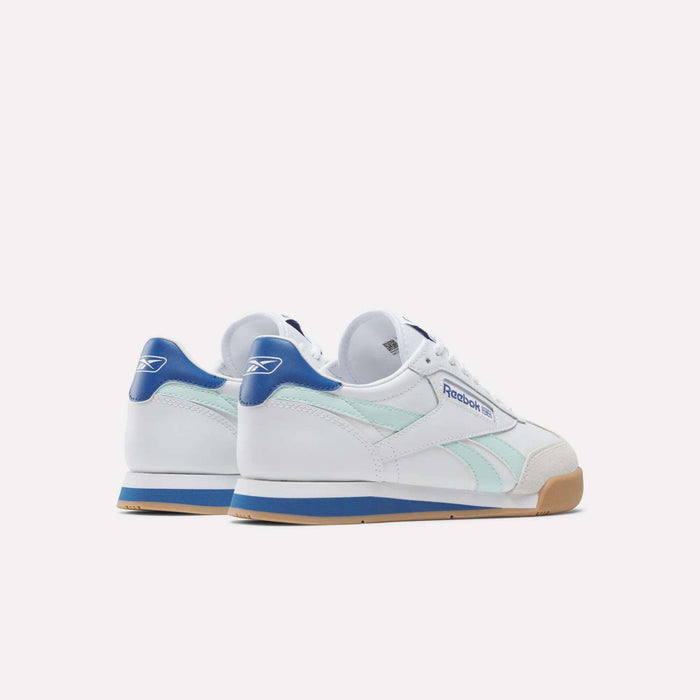 The Reebok Campio XT Shoes for Big Kids feature white uppers, light blue side stripes, blue heel tabs, gum rubber soles, and a retro soccer-inspired design with the Reebok logo on the side and heel.