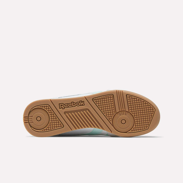 The image displays the sole of Reebok Campio XT Shoes - Big Kids, featuring a gum rubber color, textured grip patterns, and an embossed Reebok logo at the center. A light gray background accentuates the classic retro design.