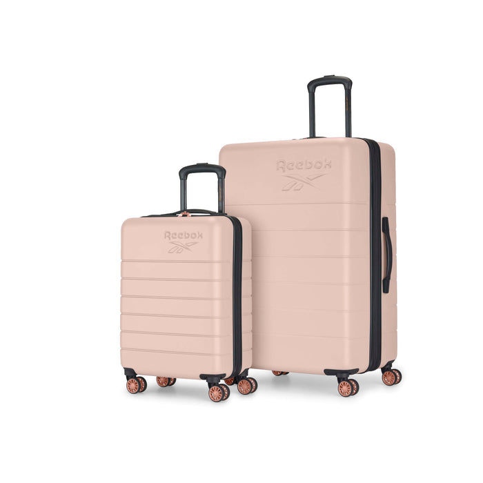 Two rose gold Reebok suitcases with black handles and wheels, one small and one large, displayed upright on a white background.