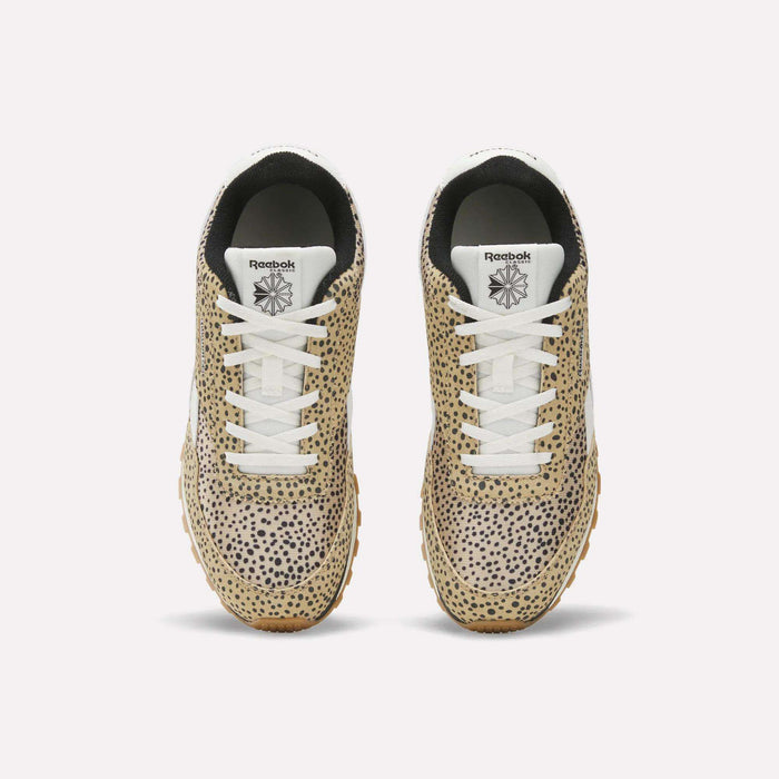 The Reebok Classic AZ Shoes for big kids feature tan uppers with a black cheetah print, white laces and soles, and black interiors, displayed from a top-down view against a plain white background.