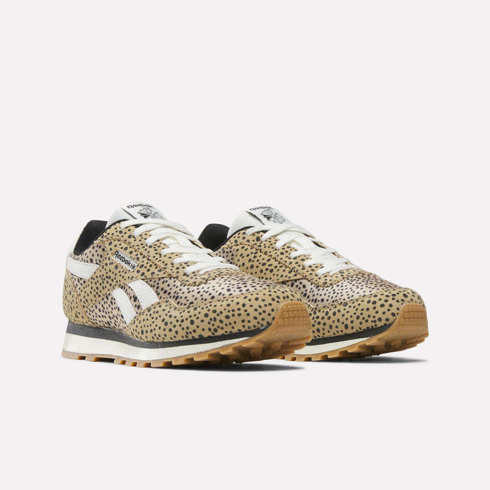 The Reebok Classic AZ Shoes for big kids feature a tan and black cheetah print, white stripes on the sides, white laces, and brown rubber soles, shown against a plain white background.