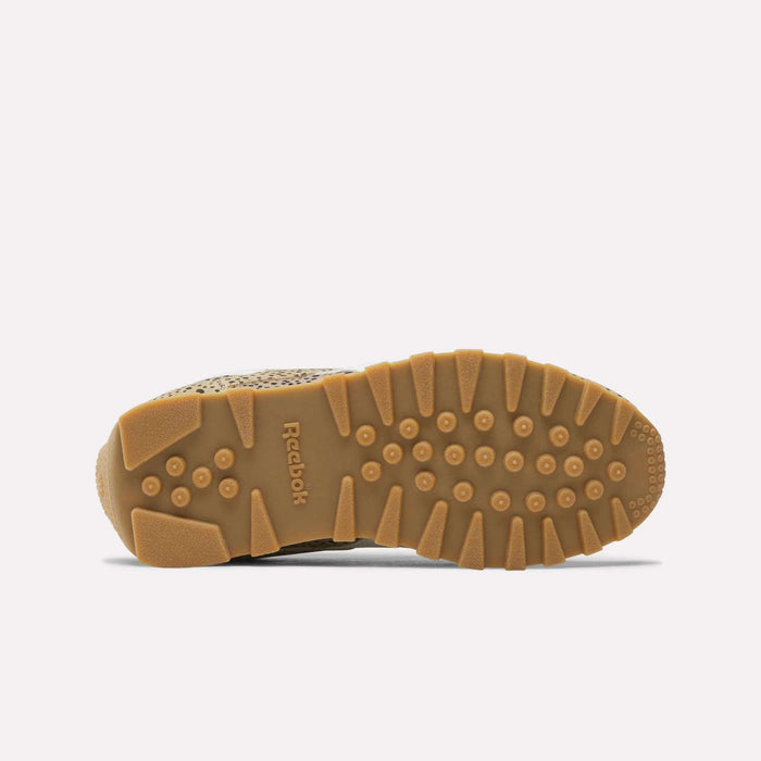 Bottom view of tan Reebok Classic AZ Shoes for big kids, these retro sneakers feature a textured gum sole with circular and rectangular treads for grip, shown against a plain white background.
