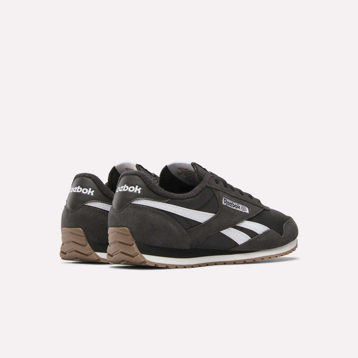 The Reebok Classic AZ Shoes feature a black design with white stripes, brown suede heel accents, and gum rubber soles, blending ’70s retro style with modern comfort, shown against a plain white background.