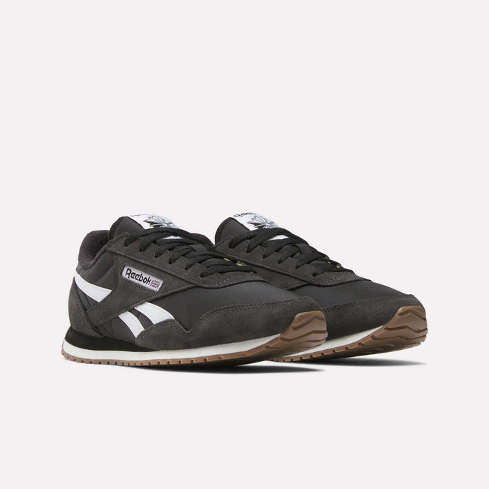 The Reebok Classic AZ Shoes feature a retro '70s design with a black upper, white stripes, gum rubber soles, and side Reebok branding, shown against a plain light background.