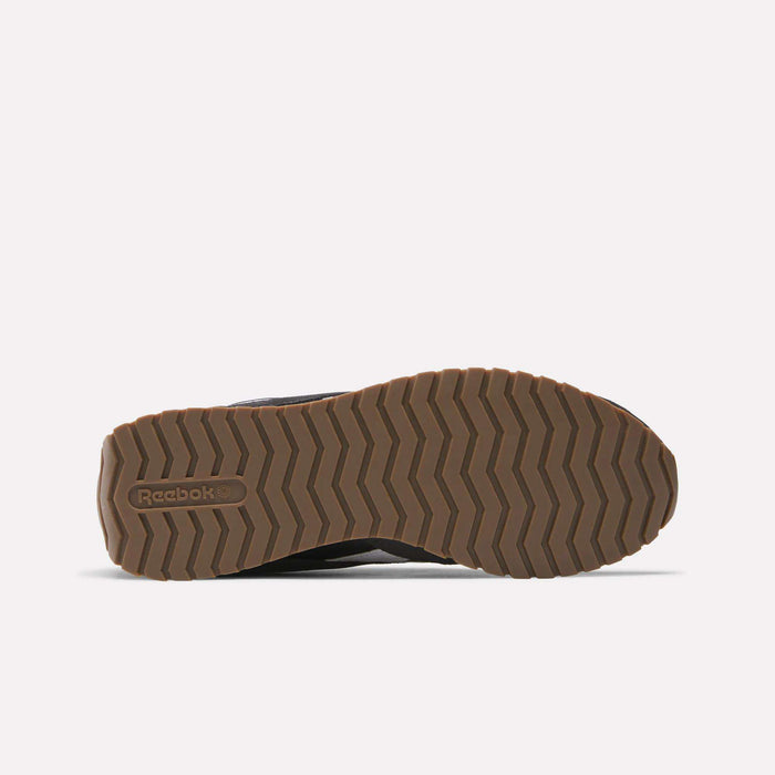 A brown rubber sole of the Reebok Classic AZ Shoes is shown from the bottom, featuring a zigzag tread pattern and the Reebok logo embossed near the heel, inspired by '70s retro running styles, against a plain white background.