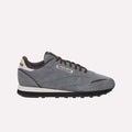 The Reebok Classic Leather Premium LTD Shoes feature a gray upper, black laces, a white and black sole, and a white heel accent—showcasing their retro-inspired silhouette against a light blue backdrop.