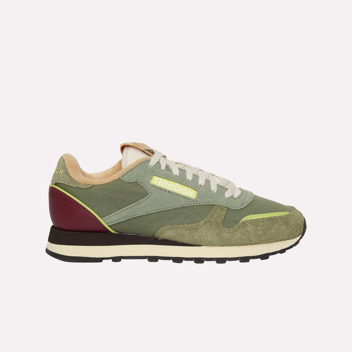 A side-profile view on a white background displays the Reebok Classic Leather Premium LTD Shoes, featuring a green suede and leather upper, beige laces, a maroon heel accent, neon yellow logo and stripe detailing, and a black sole—blending retro charm with modern flair in this classic silhouette.