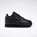 The Reebok Kids' Classic Leather Shoes - Baby & Toddler are displayed in side profile, featuring a black design with matching laces and sole, plus subtle brand details on the side and tongue against a white background.
