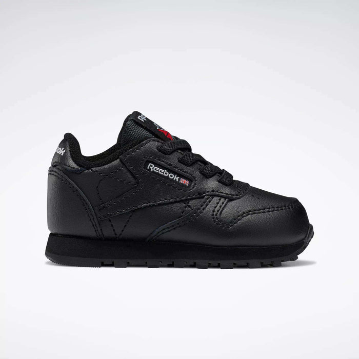 The Reebok Kids' Classic Leather Shoes - Baby & Toddler are displayed in side profile, featuring a black design with matching laces and sole, plus subtle brand details on the side and tongue against a white background.