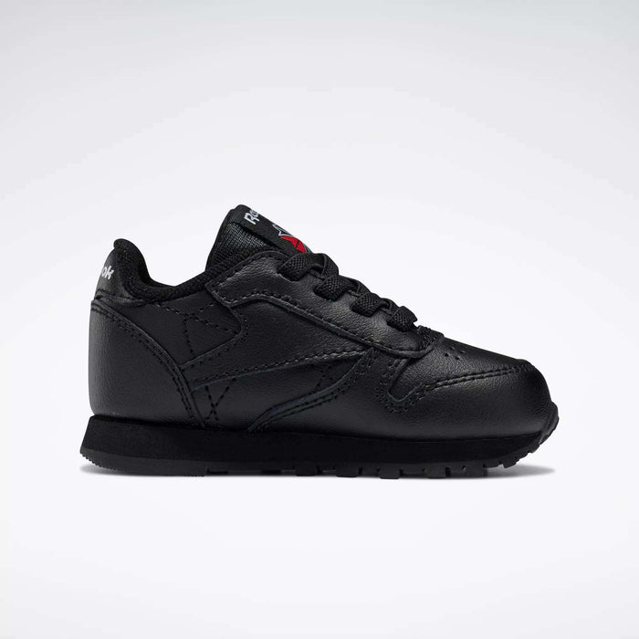 The Reebok Kids' Classic Leather Shoes - Baby & Toddler feature a black leather design with black laces and sole, shown in side profile on a white background for a timeless old-school sneaker look.