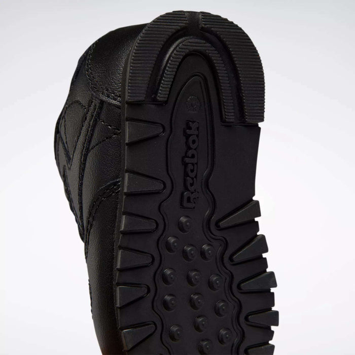 Close-up of the black rubber sole on Reebok Kids' Classic Leather Shoes for babies and toddlers, featuring a textured tread pattern and the embossed Reebok logo—an iconic detail on classic sneakers.