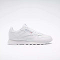 The Reebok Classic Leather Shoes - Big Kids feature an all-white, low-top design with lace-up closure, subtle side branding, and a flat rubber sole—perfect for adding minimalist style to any junior boys' shoe collection.
