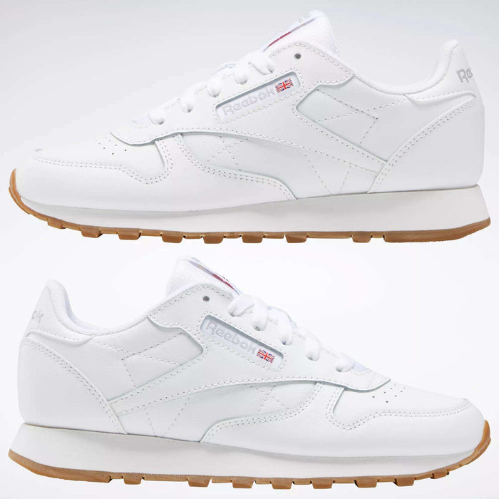 Two Reebok Classic Leather Shoes - Big Kids with gum soles and stitched side-stripes are shown side by side on a plain background, displaying both outer and inner views. The Reebok logo and Union Jack appear on the sides.