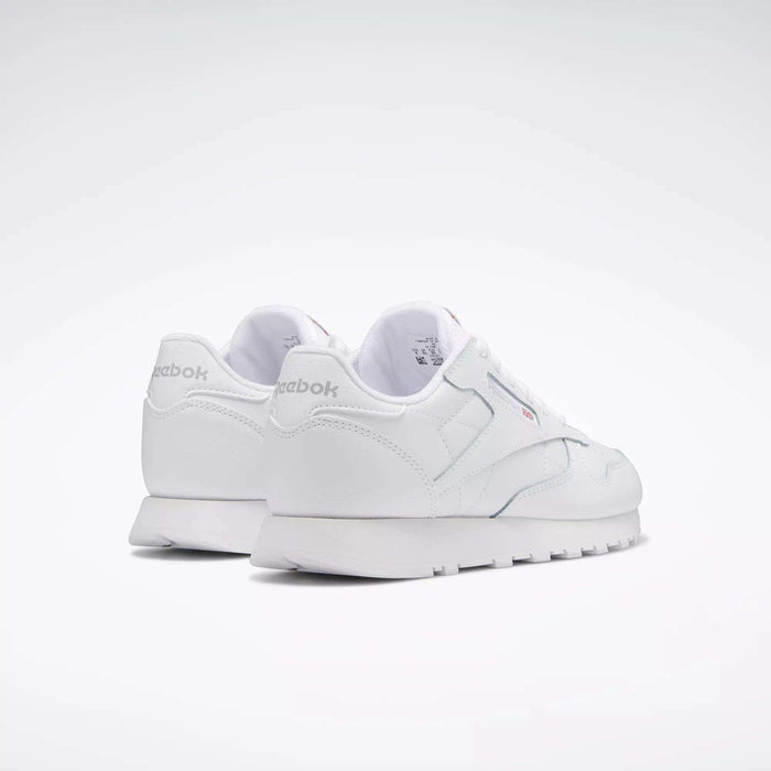 A pair of Reebok Classic Leather Shoes for big kids, shown from the rear on a plain light background. These white sneakers feature a minimal, classic design with the Reebok logo visible on the heel and side.