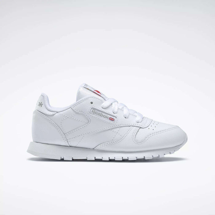 The Reebok Kids' Classic Leather Shoes - Preschool feature a white leather upper, white laces, low-top design, and subtle Reebok branding on the side and tongue, shown against a plain light background.