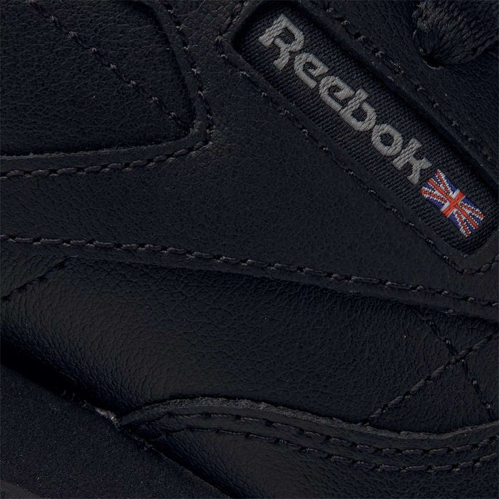 Close-up of Reebok Kids' Classic Leather Shoes - Preschool in black, showing the stitched logo and Union Jack on textured leather, designed for lightweight cushioning and all-day comfort.