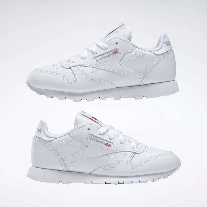 The Reebok Kids' Classic Leather Shoes - Preschool feature a white leather upper, white laces, grey soles, and subtle side and heel branding, shown on a plain white background.