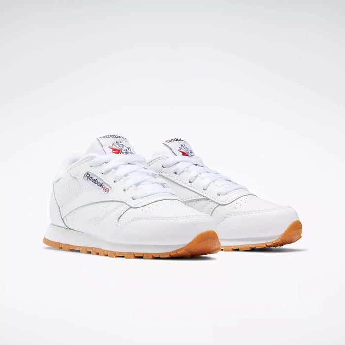 Kids' Classic Leather Shoes - Preschool by Reebok: white leather upper, gum soles, white laces, and signature Reebok logo with red and blue accents on the side and tongue. Displayed on a plain light background.