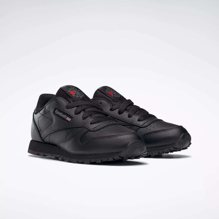 A pair of Kids' Classic Leather Shoes - Preschool by Reebok with a black leather upper, matching laces and soles, plus subtle logo accents on the side and tongue, displayed on a plain white background.