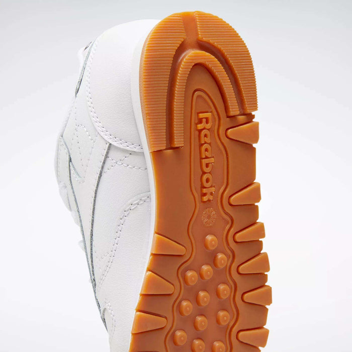 A close-up of the sole of Reebok Kids' Classic Leather Shoes – Preschool, showing a textured orange-brown rubber outsole with the Reebok logo in the center and a sturdy leather upper for extra support.