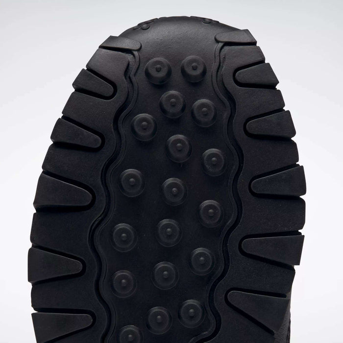 Close-up of the black sole on Reebok Kids' Classic Leather Shoes - Preschool, showing thick, rugged treads and circular indents for traction and durability, plus lightweight cushioning for all-day comfort.
