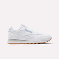 The Reebok Classic Leather Shoes are shown in white with a gum sole, blue and red Reebok side logo, and white laces, displayed in a retro-inspired side profile against a plain light background.