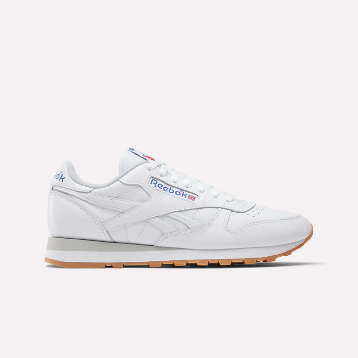 The Reebok Classic Leather Shoes are shown in white with a gum sole, blue and red Reebok side logo, and white laces, displayed in a retro-inspired side profile against a plain light background.
