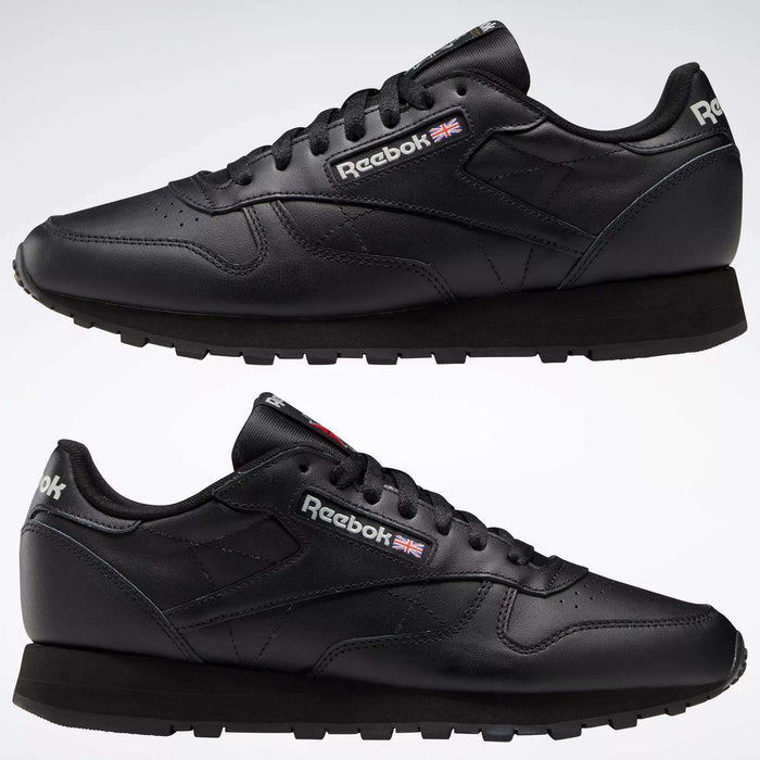 Two Reebok Classic Leather Shoes in black are displayed side by side on a white background, featuring the Reebok logo and British flag near the laces, minimalist stitching, and black rubber soles.