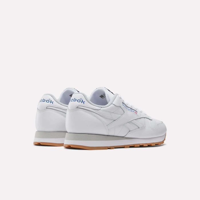 A pair of white Reebok Classic Leather Shoes with gum soles, seen from the back and side, featuring the blue Reebok logo on heel and side—ideal retro sneakers for a casual look.