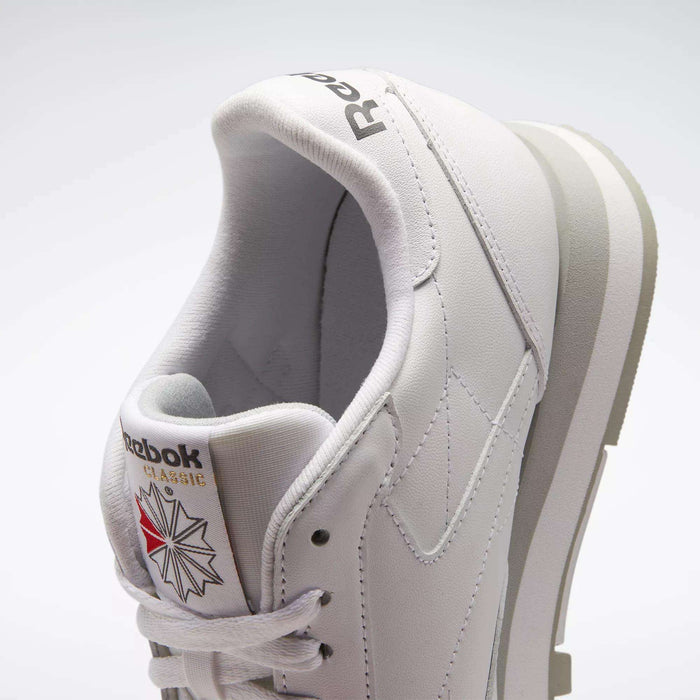 A close-up of the Reebok Classic Leather Shoes highlights their retro style, white leather upper, minimalist design, light gray sole accents, and signature tongue with Reebok logo and star graphic.