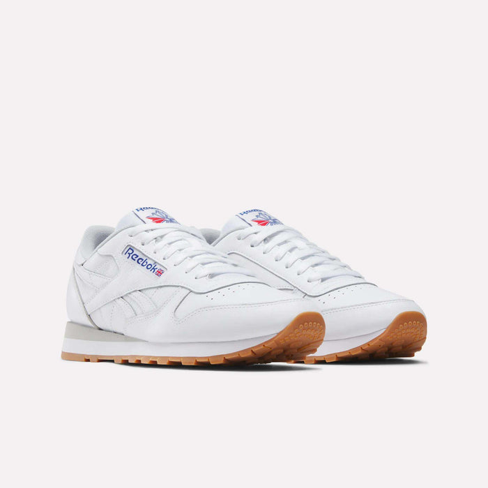 A pair of Reebok Classic Leather Shoes in white with gum soles, showing the blue and red Reebok logo on the side and tongue, presented on a plain white background for a retro-inspired style.