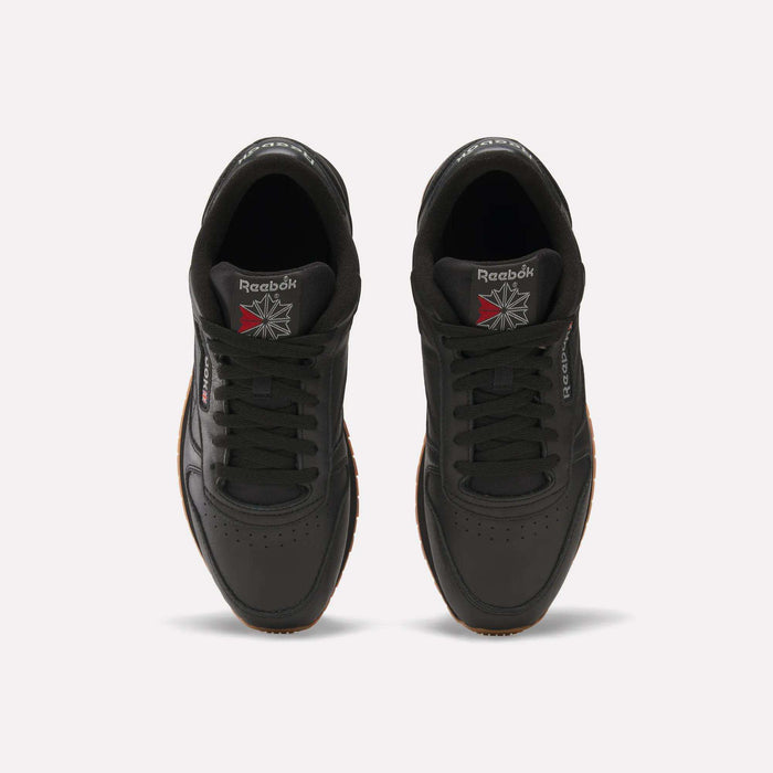 Top view of a pair of Reebok Classic Leather Shoes in black with black laces, gum soles, and the Reebok logo on the tongues and sides. Durable leather and retro design stand out against a white background.